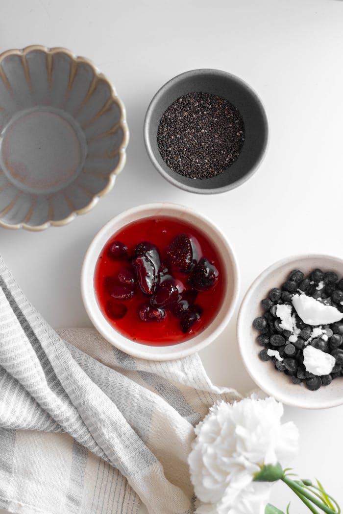 Flat lay of chia seeds, berries, and yogurt in a white setting, perfect for health blogs.