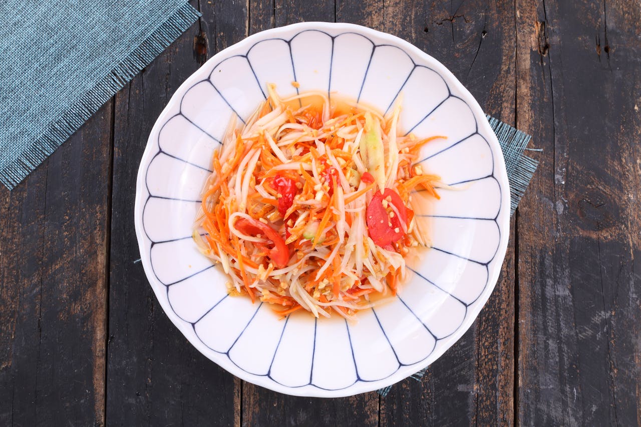 A colorful Thai papaya salad served on a wooden table.